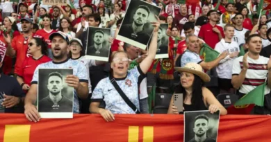 Les fans portugais ont des photos de Diogo Jota à l'intérieur d'un stade, une jeune fille dans des lunettes et deux drapeaux portugais peints sur ses joues à l'avant entre un homme et une femme. Derrière eux, plusieurs fans des kits de football rouge et vert du Portugal et des écharpes